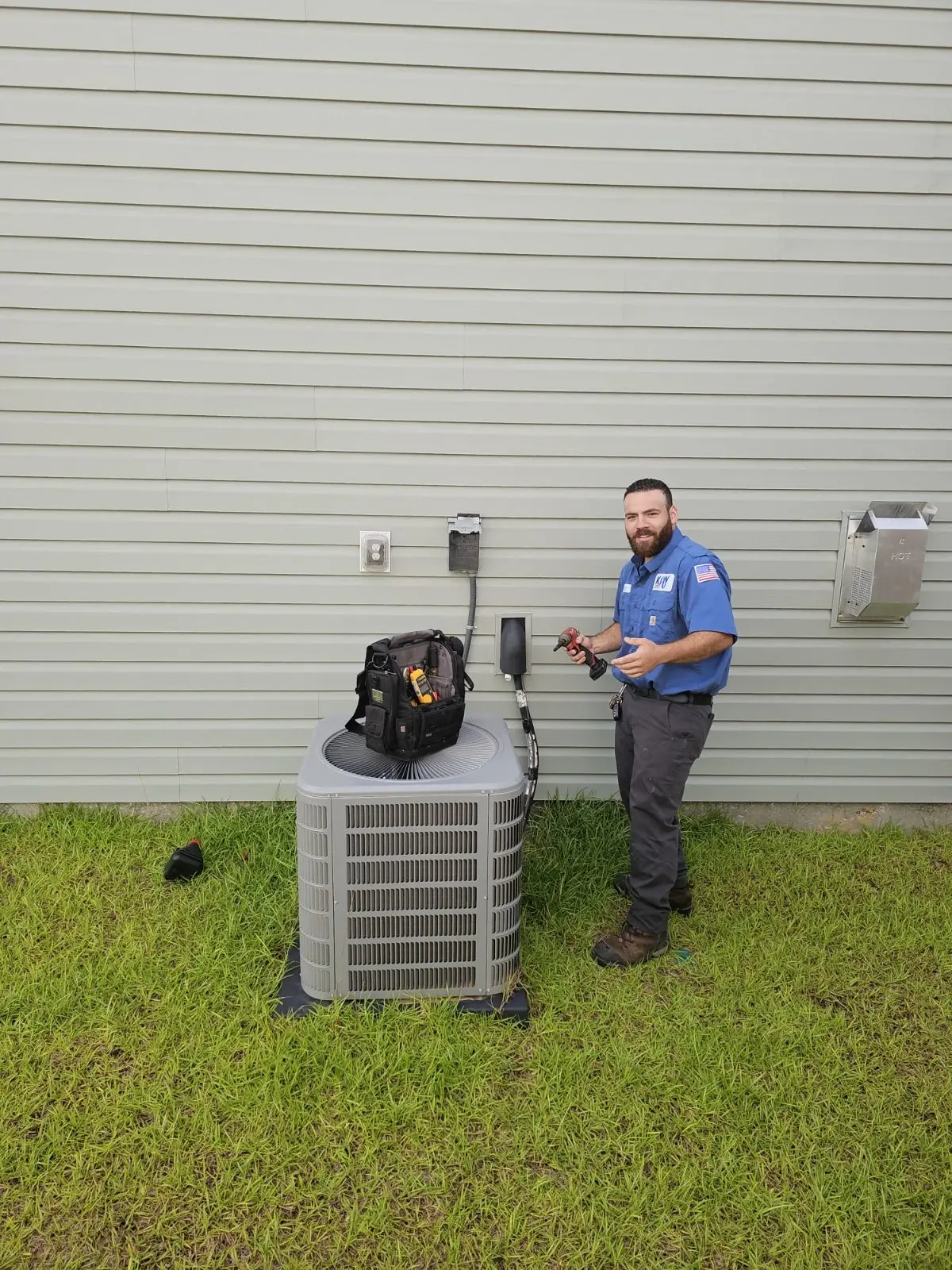 HVAC technician performing maintenance on an outdoor air conditioning unit.